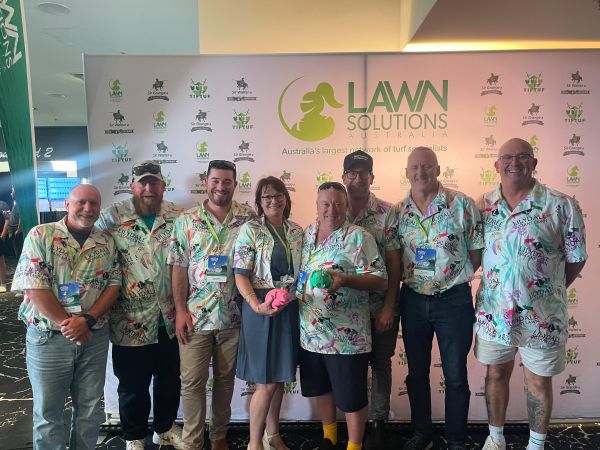 Lilydale Instant Lawn team members smiling in front of a Lawn Solutions backdrop.