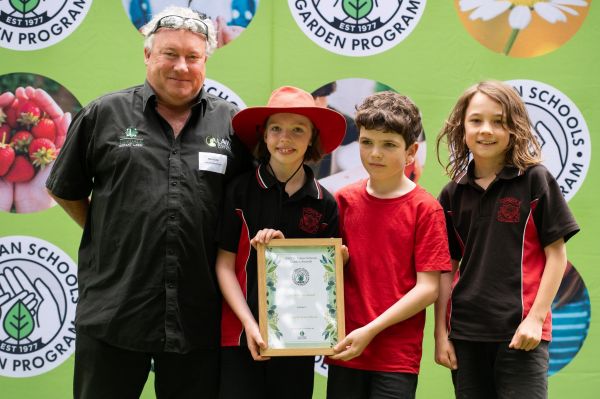 Three students and a Lilydale Instant Lawn representative holding a 2025 Victorian Schools Garden Award certificate.