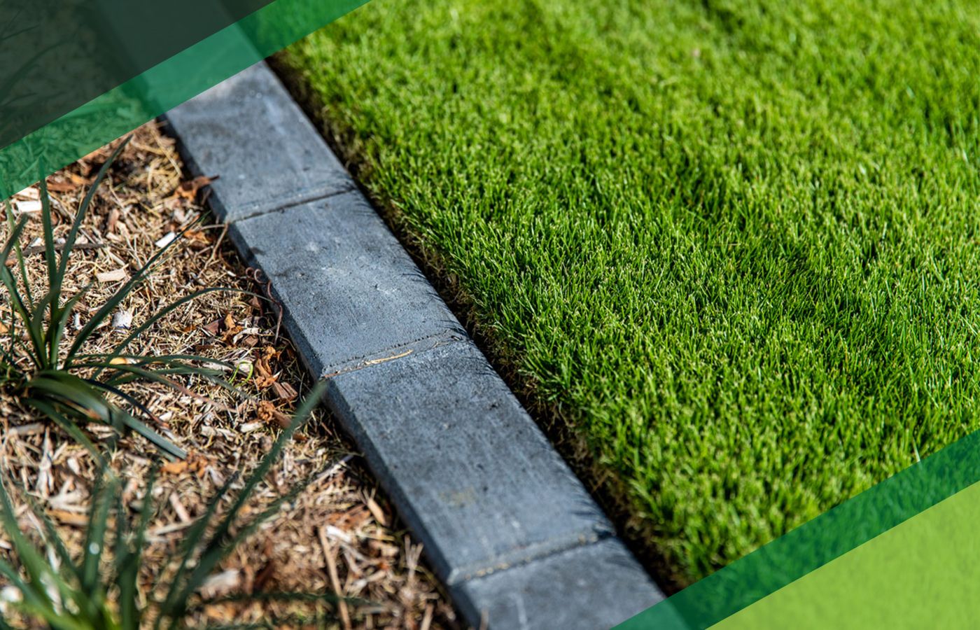 Concrete garden edging separates a mulched planting bed from a neatly trimmed green lawn, shown in close-up.