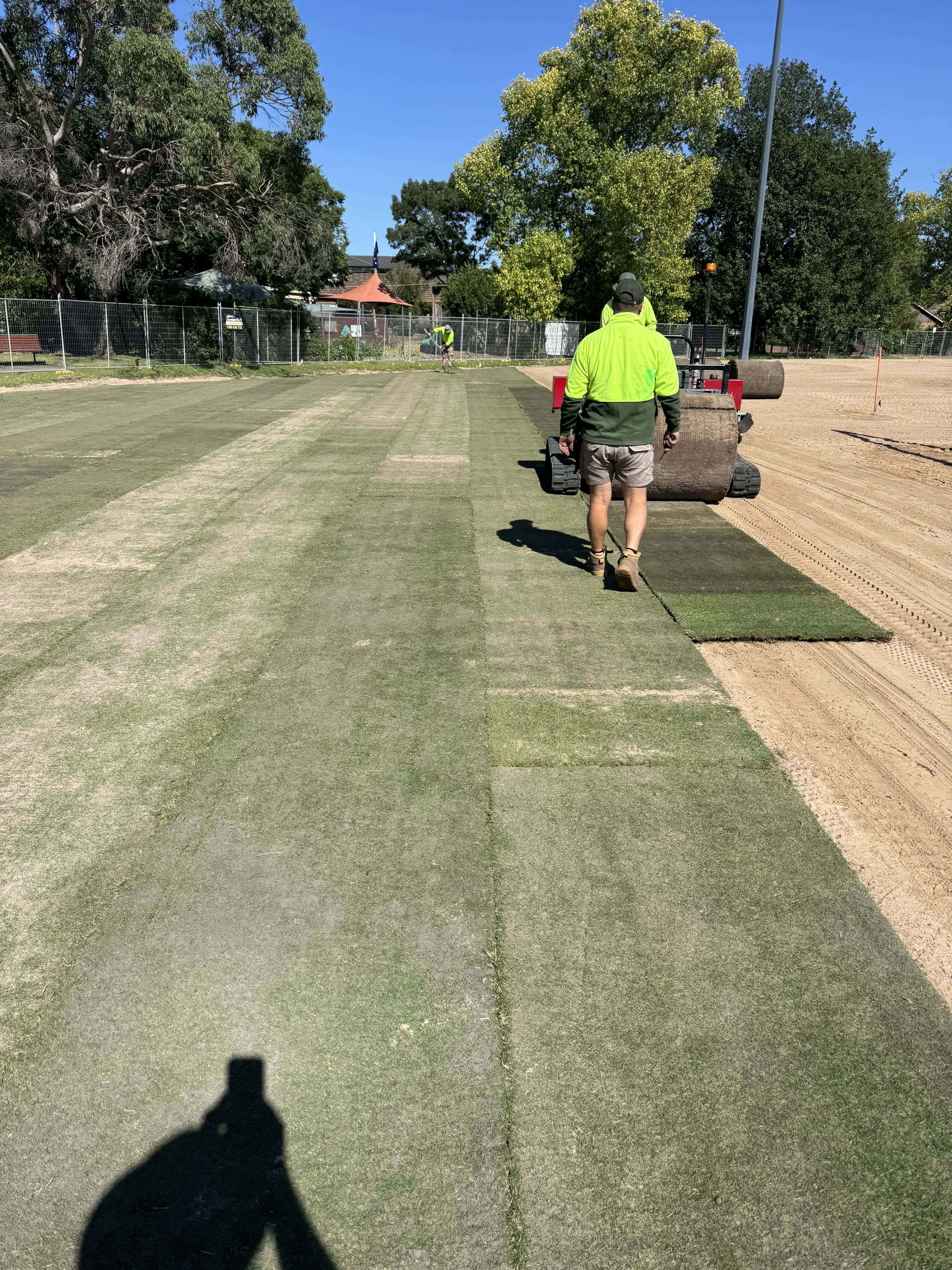 Worker laying turf on a sports field