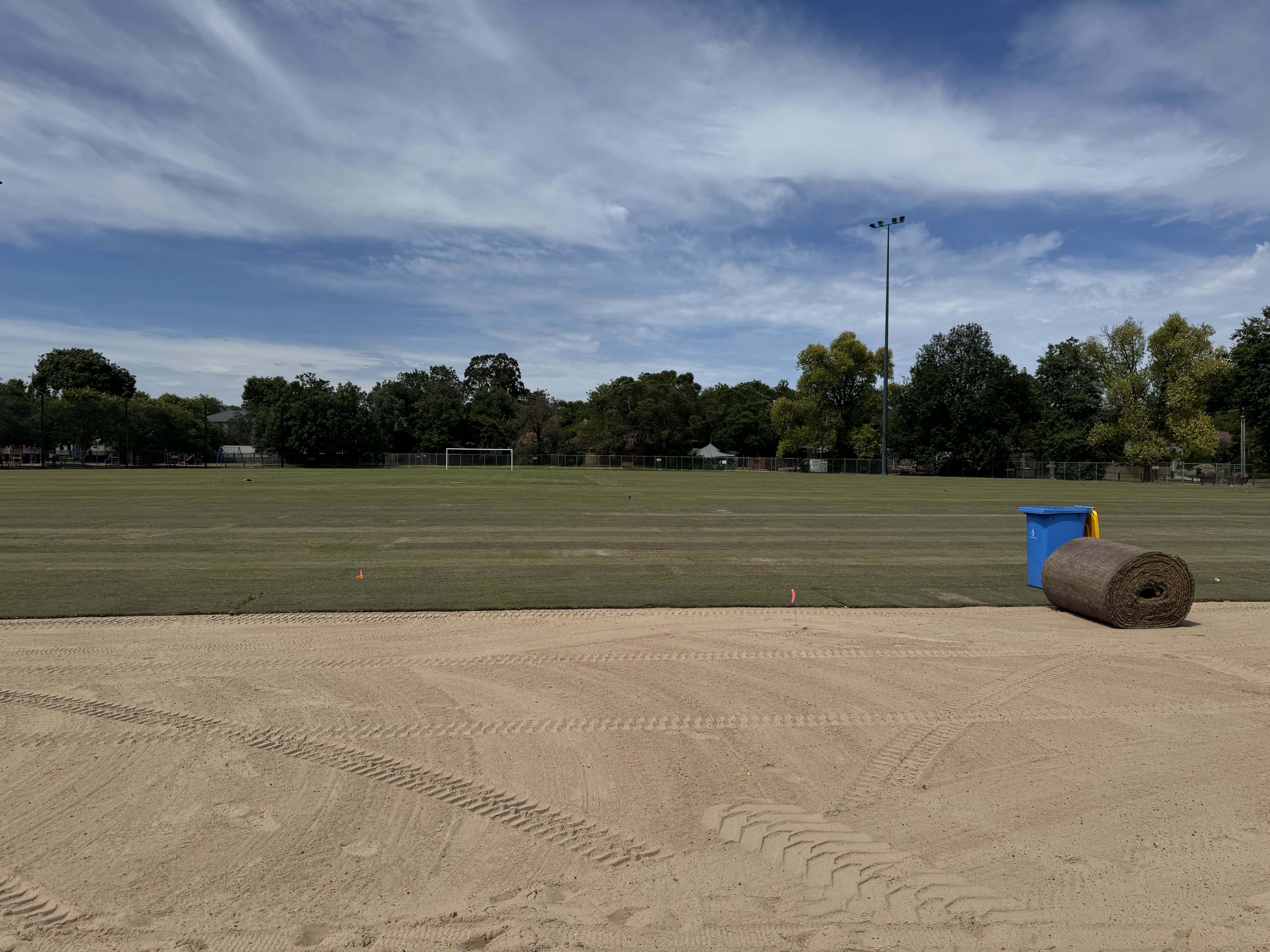 Freshly laid sports turf beside a sandy edge