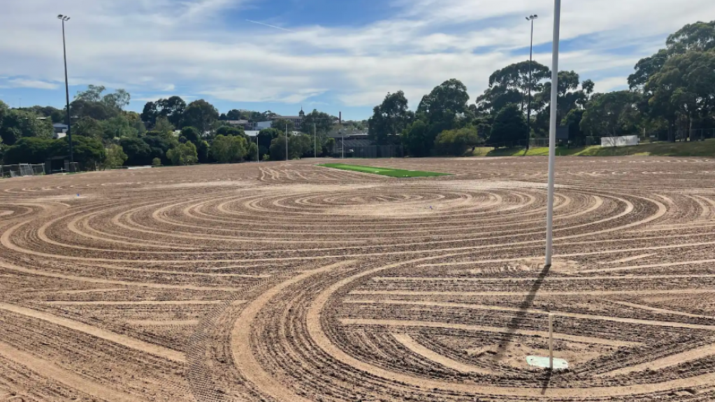 Prepared sports field base with graded sand and circular rake lines