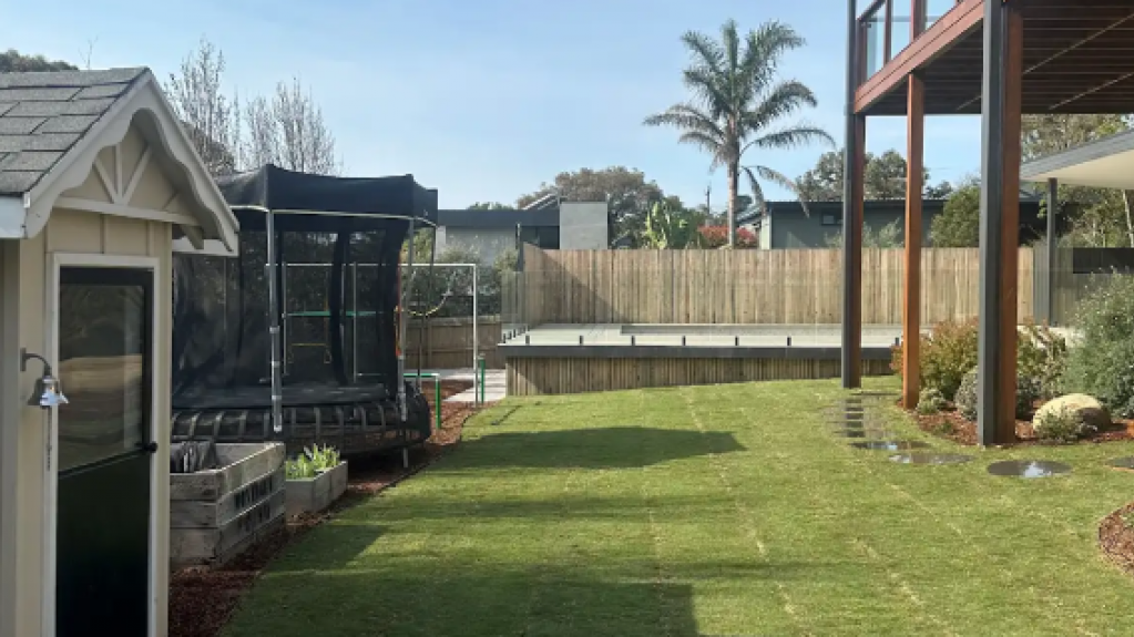 Backyard in Mt Eliza following a pool renovation, featuring freshly laid TifTuf Bermuda turf and landscaped garden beds for a clean, modern finish.