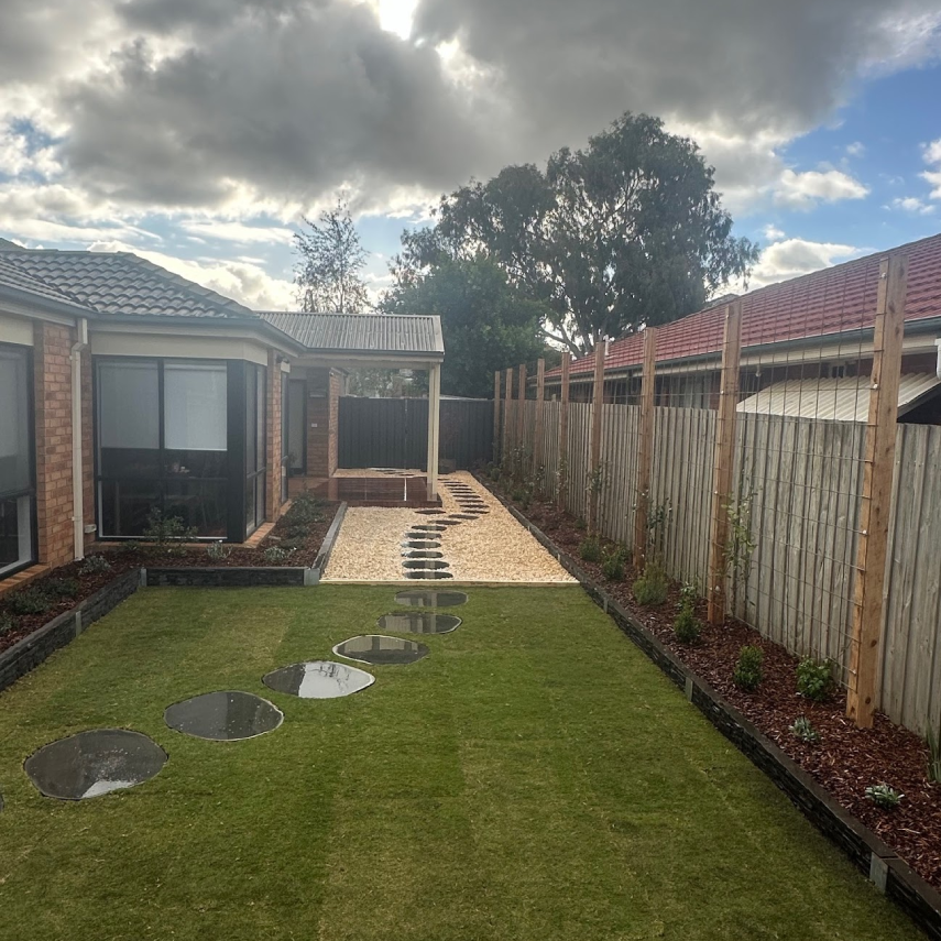 Completed backyard with lawn, stepping stones, gravel path and plants
