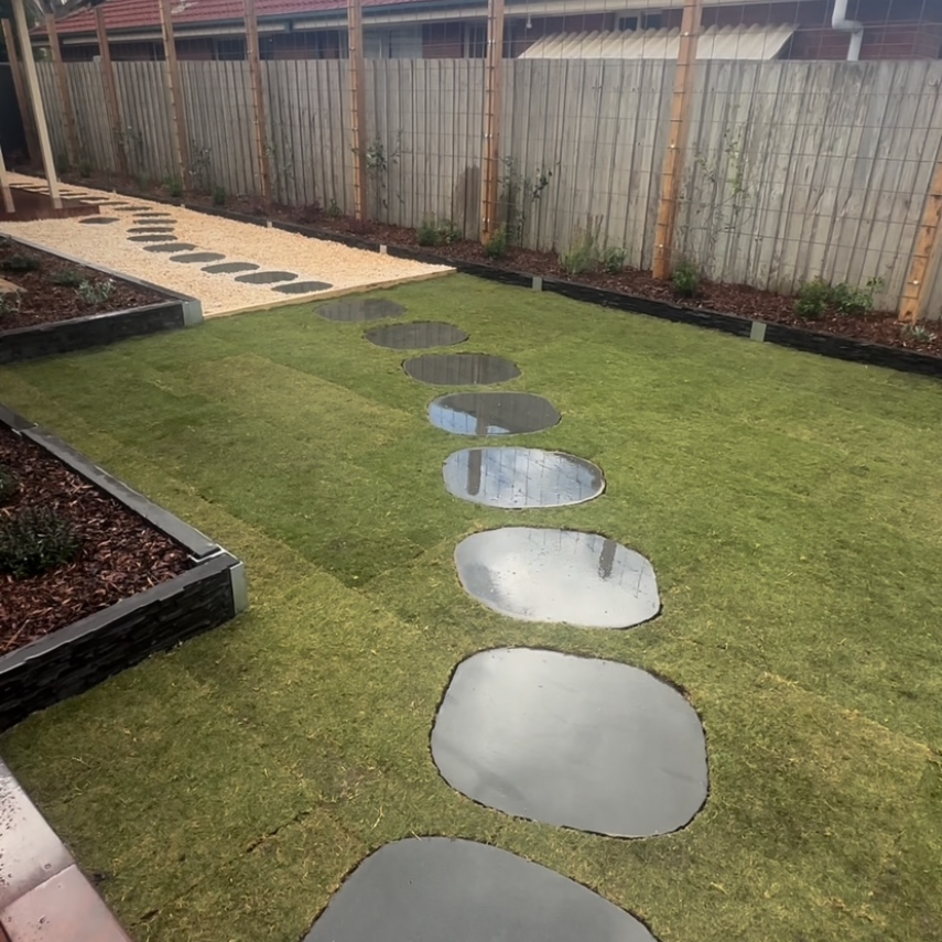 Stepping stones set into lawn beside gravel path and garden beds