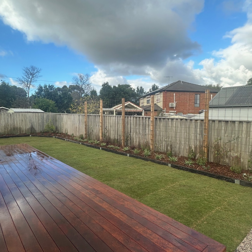 Landscaped backyard with lawn, deck and planted fence border