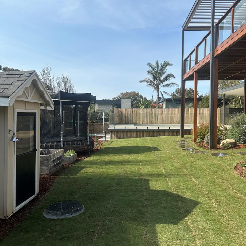 Backyard lawn with trampoline, stepping stones and raised pool deck