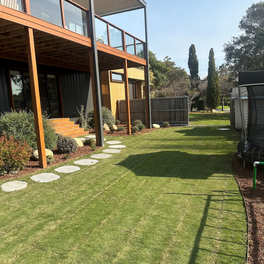 Rear garden lawn beside a raised timber deck and planted border