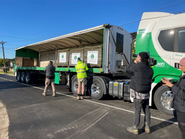 Two Lilydale staff unloading paddocks of turf from a delivery truck as a cameraman from Selling Houses Australia films them. 